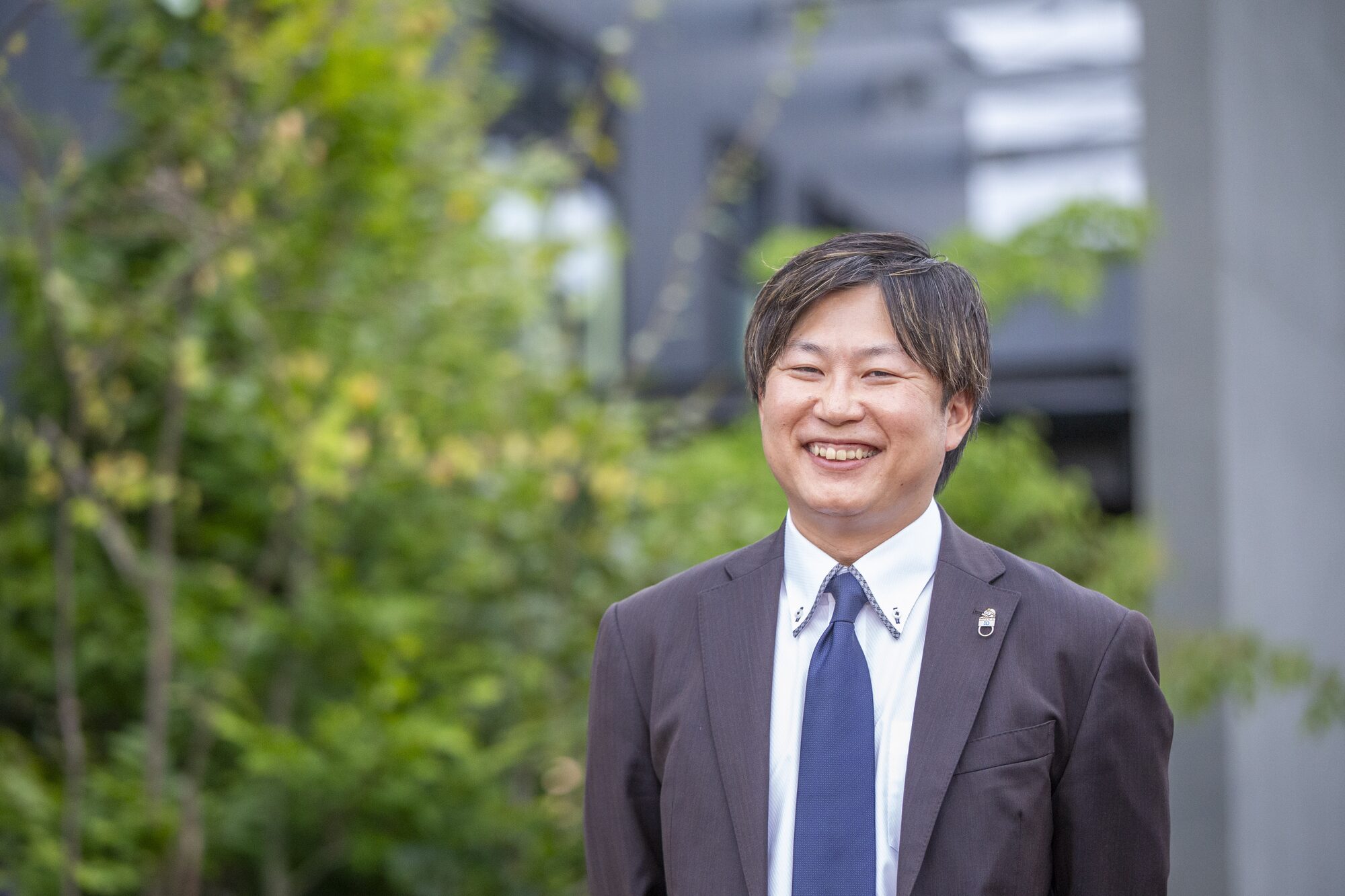 社屋の前で笑顔を見せる代表取締役 居藤正人